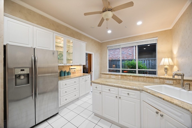 kitchen featuring stainless steel fridge, a sink, light tile patterned floors, ornamental molding, and glass insert cabinets