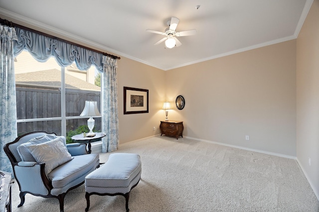 sitting room with a ceiling fan, baseboards, crown molding, and carpet