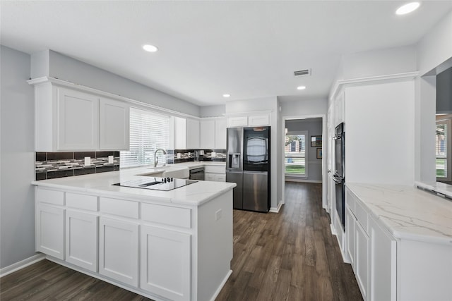kitchen featuring black appliances, a peninsula, backsplash, white cabinetry, and recessed lighting