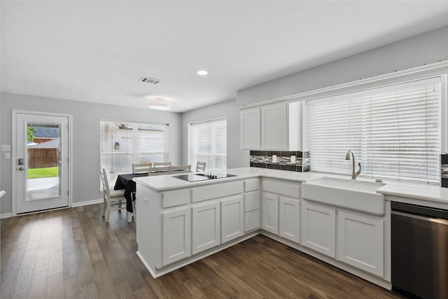 kitchen featuring dishwasher, a sink, a peninsula, black electric cooktop, and light countertops