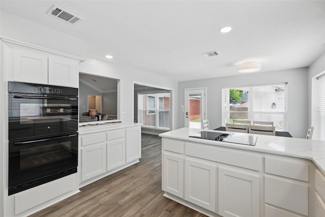 kitchen with black appliances, light countertops, wood finished floors, white cabinets, and recessed lighting