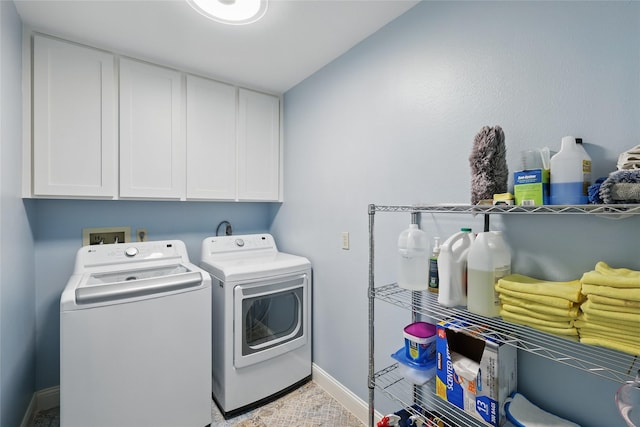 clothes washing area featuring separate washer and dryer, baseboards, and cabinet space