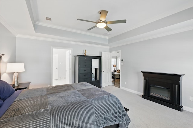 carpeted bedroom featuring a tray ceiling, crown molding, a glass covered fireplace, and baseboards