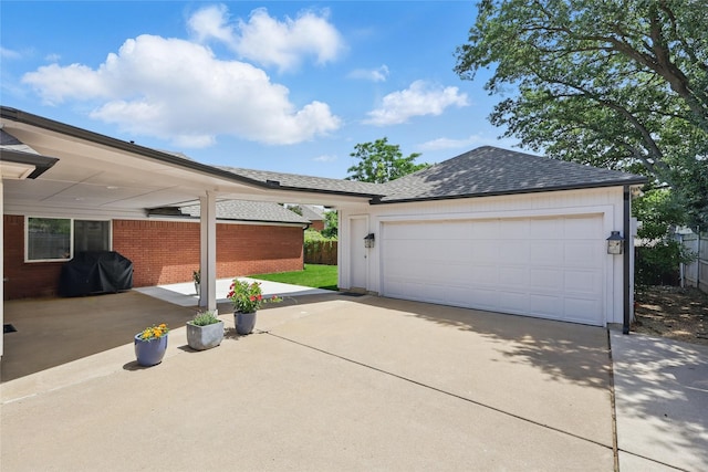garage featuring concrete driveway and fence