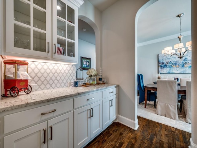 6209 Crystal Cove Ct, Mckinney, TX 75071 - bar area with a chandelier, tasteful backsplash, dark wood-type flooring, arched walkways, and decorative light fixtures