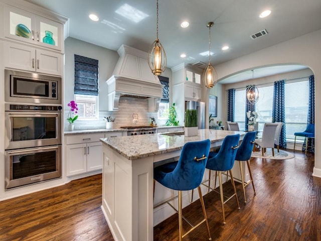 6209 Crystal Cove Ct, Mckinney, TX 75071 - kitchen with appliances with stainless steel finishes, custom exhaust hood, white cabinets, backsplash, and glass insert cabinets