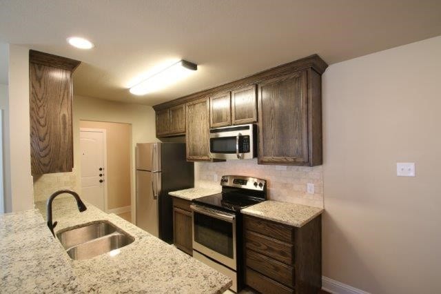 8036 Doreen Ave, Fort Worth, TX 76116 - kitchen with appliances with stainless steel finishes, a sink, backsplash, light stone countertops, and recessed lighting