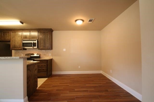 8036 Doreen Ave, Fort Worth, TX 76116 - kitchen featuring appliances with stainless steel finishes, dark wood finished floors, light countertops, baseboards, and backsplash