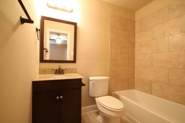 8036 Doreen Ave, Fort Worth, TX 76116 - bathroom with toilet, vanity, baseboards, and shower / washtub combination