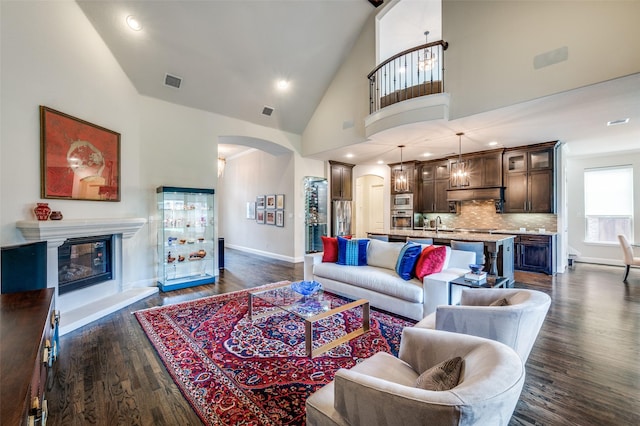 4388 Argyle Ln, Frisco, TX 75034 - living area with arched walkways, dark wood-style floors, a glass covered fireplace, baseboards, and high vaulted ceiling