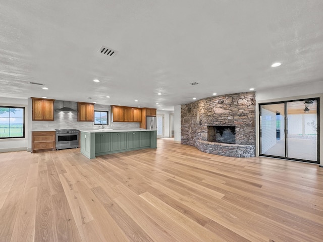 1551 Lower Tonk Valley Rd, Graham, TX 76450 - unfurnished living room with light wood finished floors, recessed lighting, a stone fireplace, and a sink