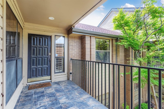 5158 Westgrove Dr, Dallas, TX 75248 - doorway to property featuring a balcony, a shingled roof, and brick siding