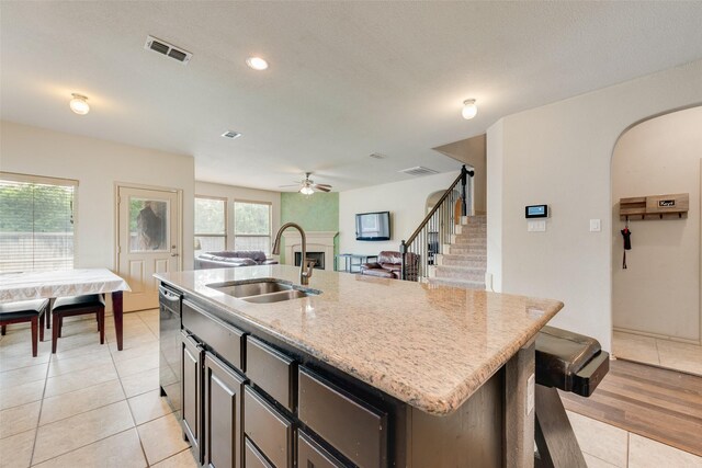 6712 Eliza Dr, Arlington, TX 76001 - kitchen featuring a sink, a fireplace, light stone counters, ceiling fan, and light tile patterned floors