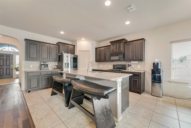 6712 Eliza Dr, Arlington, TX 76001 - kitchen featuring black microwave, gas range oven, stainless steel fridge with ice dispenser, arched walkways, and backsplash