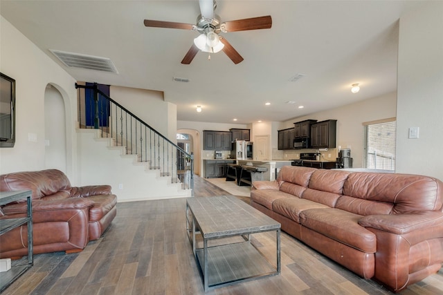 6712 Eliza Dr, Arlington, TX 76001 - living area featuring arched walkways, ceiling fan, stairway, wood finished floors, and recessed lighting