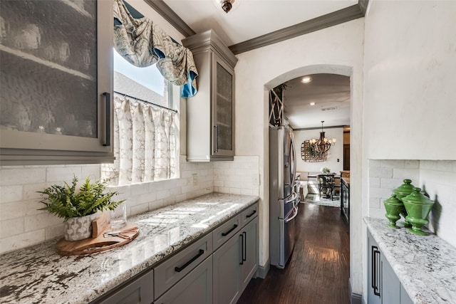 2466 Campfire Ln, Frisco, TX 75033 - kitchen featuring stainless steel refrigerator with ice dispenser, crown molding, light stone counters, tasteful backsplash, and glass insert cabinets