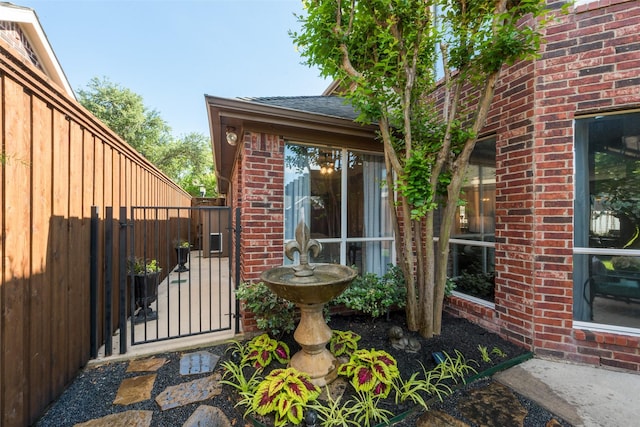 2466 Campfire Ln, Frisco, TX 75033 - view of exterior entry with brick siding, a gate, and roof with shingles