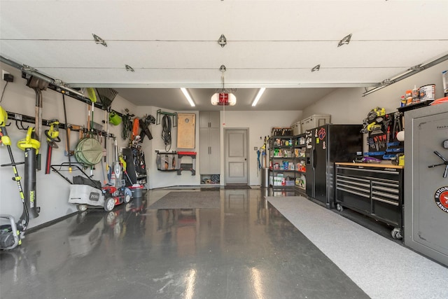2466 Campfire Ln, Frisco, TX 75033 - garage with black refrigerator with ice dispenser and a workshop area