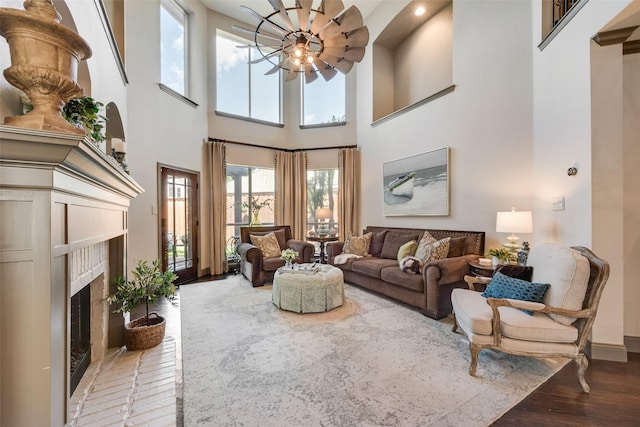 2466 Campfire Ln, Frisco, TX 75033 - living room featuring a fireplace, light wood-type flooring, a high ceiling, ceiling fan, and baseboards