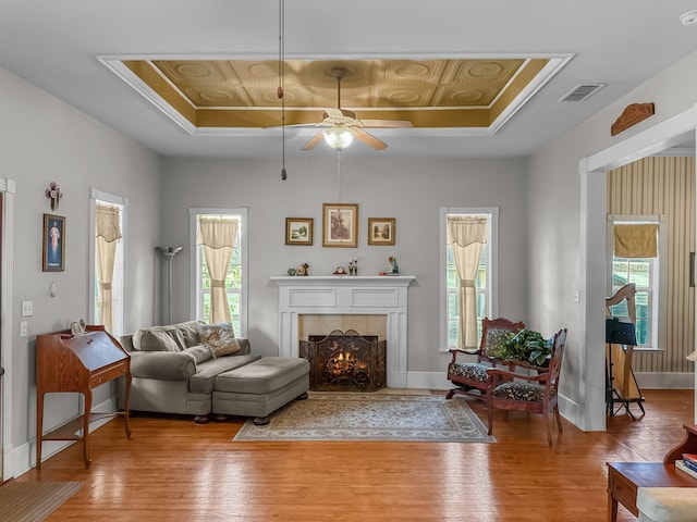 303 E Mclain, Iredell, TX 76649 - living room with a raised ceiling, wood finished floors, a ceiling fan, a tiled fireplace, and ornamental molding