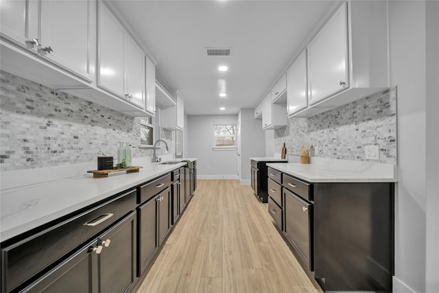 1213 Bowie St, Garland, TX 75040 - kitchen with white cabinetry, a sink, light wood-style flooring, decorative backsplash, and recessed lighting