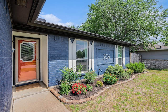 704 Vaughn Dr, Burleson, TX 76028 - view of exterior entry featuring brick siding and a lawn