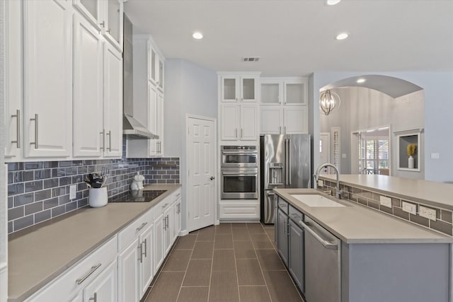 6436 Branchwood Trl, The Colony, TX 75056 - kitchen with stainless steel appliances, a sink, tasteful backsplash, white cabinetry, and wall chimney range hood
