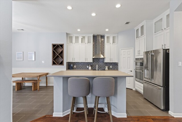 6436 Branchwood Trl, The Colony, TX 75056 - kitchen featuring appliances with stainless steel finishes, wall chimney range hood, white cabinetry, a center island, and recessed lighting