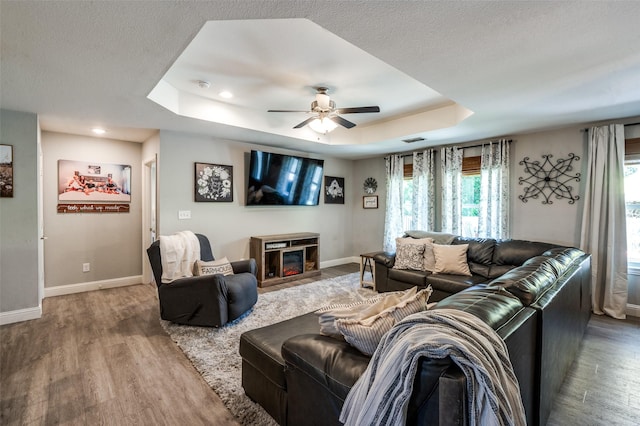 211 Hilltop Cir, Blue Ridge, TX 75424 - living room with a tray ceiling, baseboards, wood finished floors, a ceiling fan, and a glass covered fireplace