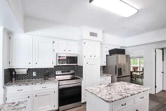 19413 US Highway 79 E, Jacksonville, TX 75766 - kitchen with appliances with stainless steel finishes, wood finished floors, tasteful backsplash, white cabinetry, and crown molding