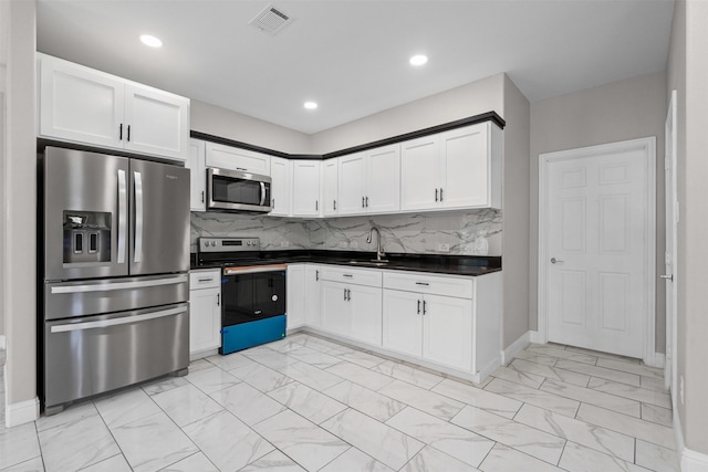 2636 Carter Ave, Fort Worth, TX 76103 - kitchen featuring stainless steel appliances, light marble finish floors, dark countertops, a sink, and white cabinetry