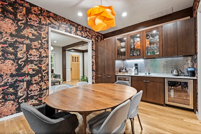 dining room with beverage cooler, wet bar, light wood-style floors, and recessed lighting