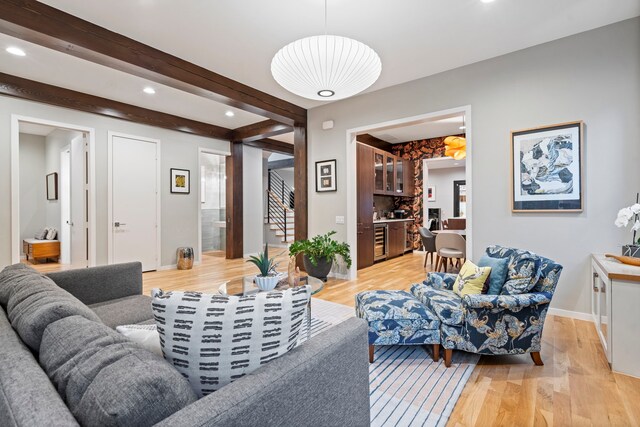 living room with light wood-style floors, recessed lighting, baseboards, stairway, and beamed ceiling