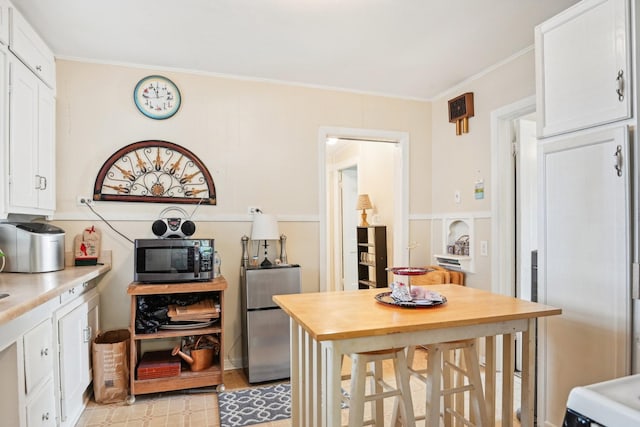 2509 Bird St, Fort Worth, TX 76111 - kitchen with appliances with stainless steel finishes, white cabinets, crown molding, and wooden counters