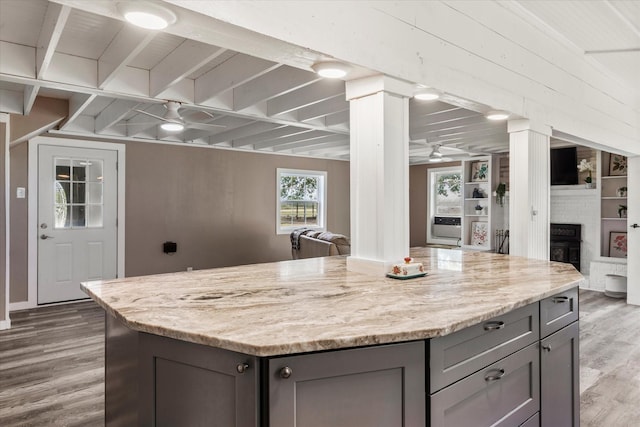 7928 Farm Rd Unit 127, Mount Pleasant, TX 75455 - kitchen featuring gray cabinetry, wood finished floors, a ceiling fan, a kitchen island, and a large fireplace