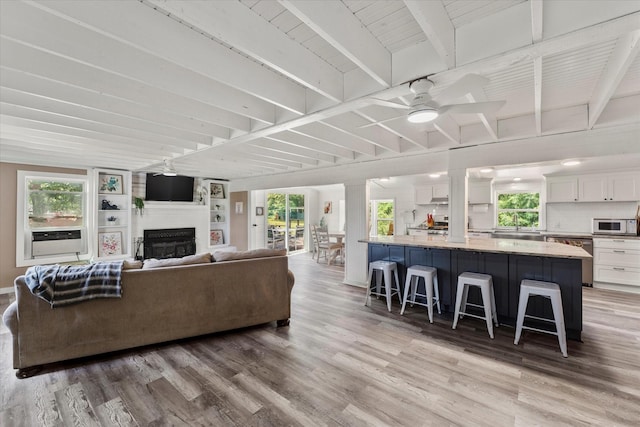 7928 Farm Rd Unit 127, Mount Pleasant, TX 75455 - living room featuring light wood-type flooring, ceiling fan, a fireplace, beamed ceiling, and baseboards
