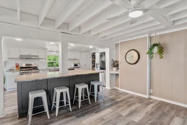 7928 Farm Rd Unit 127, Mount Pleasant, TX 75455 - kitchen with appliances with stainless steel finishes, white cabinetry, light wood finished floors, under cabinet range hood, and a spacious island