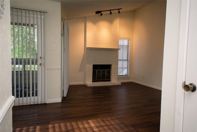 1101 Quail Valley Ln Unit 211, Arlington, TX 76011 - unfurnished living room with wood finished floors, track lighting, a brick fireplace, and baseboards