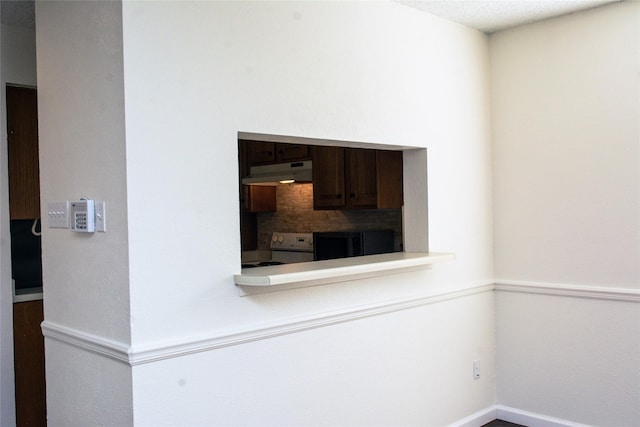 1101 Quail Valley Ln Unit 211, Arlington, TX 76011 - kitchen featuring under cabinet range hood, white range with electric stovetop, baseboards, and light countertops