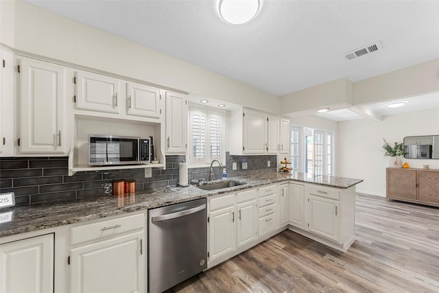 2935 Maydelle Ln, Farmers Branch, TX 75234 - kitchen featuring appliances with stainless steel finishes, a sink, decorative backsplash, white cabinetry, and stone countertops