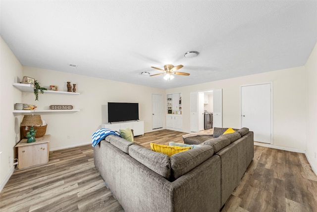 2935 Maydelle Ln, Farmers Branch, TX 75234 - living room featuring wood finished floors, baseboards, ceiling fan, and separate washer and dryer