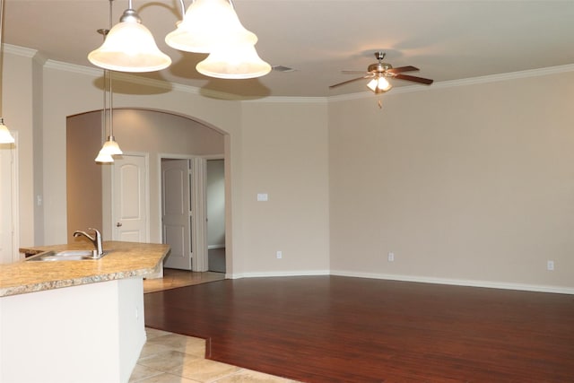 414 Stonecreek Dr, Princeton, TX 75407 - kitchen with a sink, arched walkways, a ceiling fan, ornamental molding, and light wood-style flooring