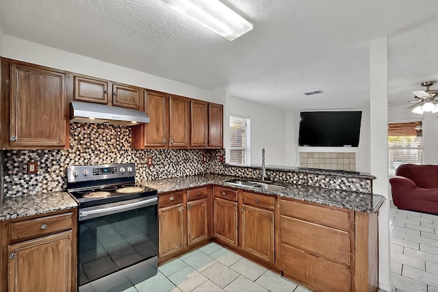 kitchen featuring stainless steel electric stove, under cabinet range hood, open floor plan, a sink, and plenty of natural light