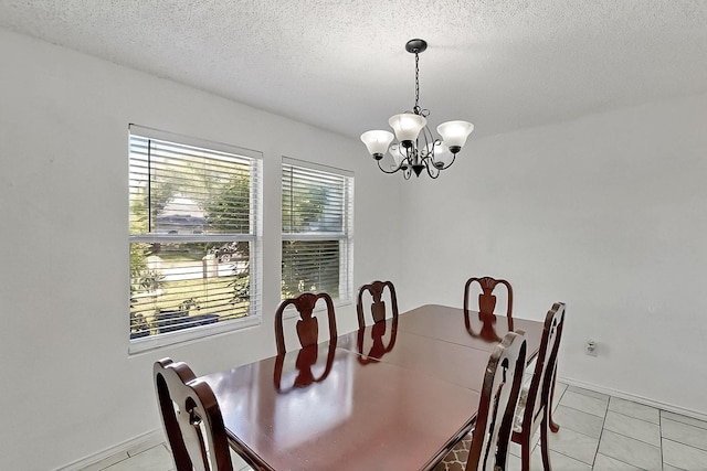 dining area with a chandelier, light tile patterned floors, a textured ceiling, and baseboards