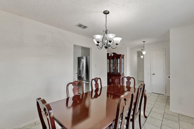 dining room featuring a chandelier, light tile patterned floors, and a textured ceiling