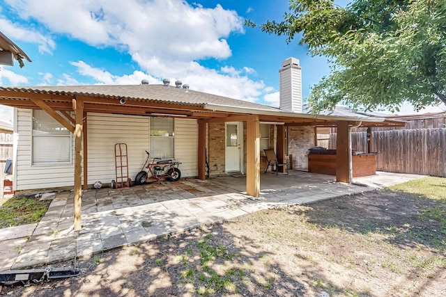 back of house featuring a patio, fence, and a chimney