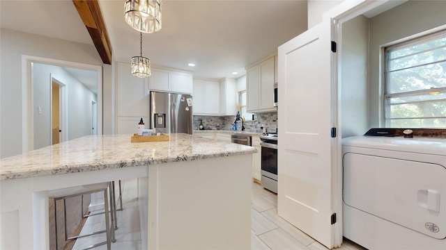 1408 Briarwood Blvd, Arlington, TX 76013 - kitchen with washer / clothes dryer, stainless steel appliances, tasteful backsplash, a center island, and light stone countertops