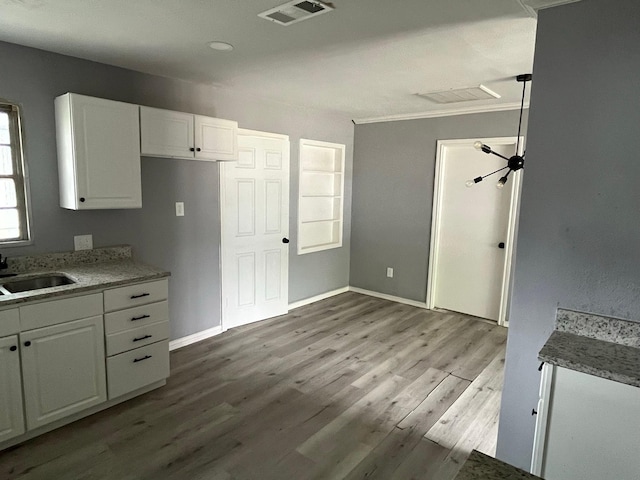 2836 Modree Ave, Dallas, TX 75216 - kitchen featuring a sink, white cabinetry, wood finished floors, baseboards, and light stone counters