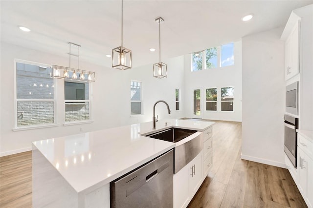 220 E Park St, Little Elm, TX 75068 - kitchen featuring stainless steel appliances, a kitchen island with sink, light countertops, a sink, and light wood-type flooring