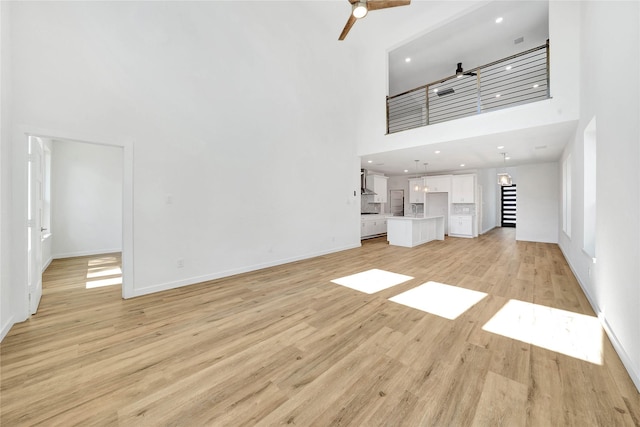 220 E Park St, Little Elm, TX 75068 - unfurnished living room with a towering ceiling, a ceiling fan, light wood-style flooring, baseboards, and recessed lighting